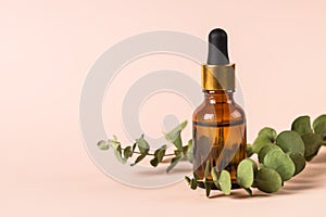 Serum bottle with fresh leaves at pastel background.