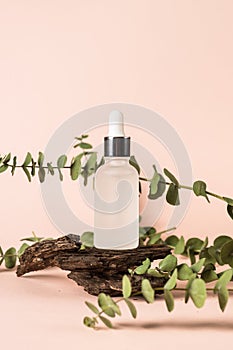 Serum bottle with fresh leaves at pastel background.