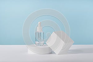 Serum cosmetic bottle with peptides and retinol on platform pedestal on blue background. Oil cosmetics transparent