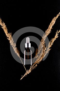 Serum or essential oil bottle isolated on black background. Beauty product concept.