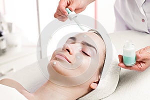 Serum facial treatment of young woman in spa salon photo