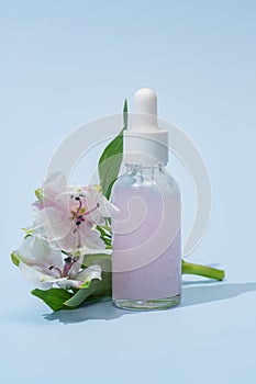 Serum with floral extracts for skincare. Nature cosmetics in glass bottle with pipette and pink alstromeria flowers on