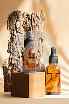 Serum in glass bottle with dropper lid on stand made of natural wood. Mockup of container with dropper lid with collagen