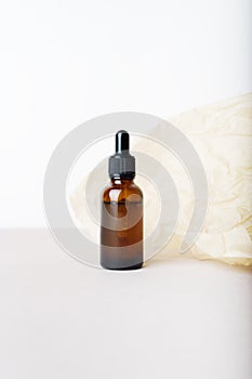 Serum glass bottle with pipette on beige wrinkle paper background.