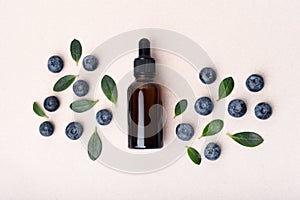 Serum glass dropper bottle with blueberries on light beige background.