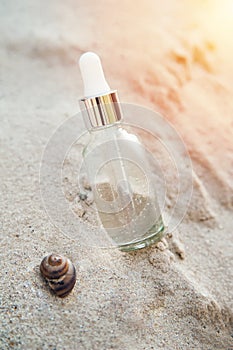 Serum oil and snail close-up on textured natural sand