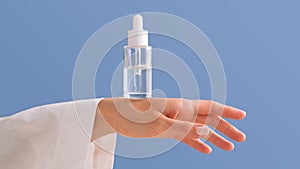 Serum with a pipette in female hands on a blue background.