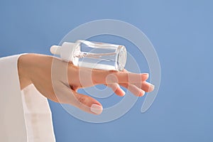 Serum with a pipette in female hands on a blue background.