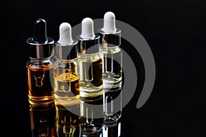 serums in glass droppers on reflective black base photo