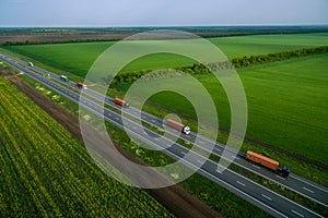 serval trucks whith container  driving on asphalt road along the green fields.