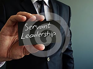 Servant leadership concept. Black piece of paper in the hand photo