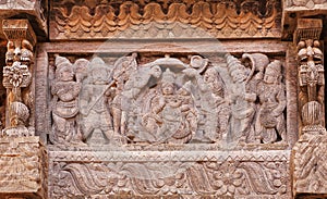 Servants and admirers of the Indian god on carved wooden wall of traditional Hindu temple.