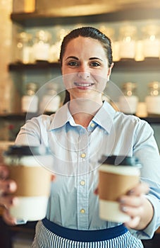 We only serve the freshest. Portrait of a young barista holding cups of coffee in a cafe.