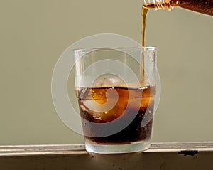 Serve a glass cup and ice cubes with cola