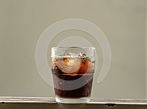 Serve a glass cup and ice cubes with cola