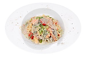 Serve pasta with red fish and vegetables on white plate.