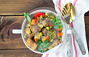 Served beef meat stewed with vegetables in ceramic pot on wooden background