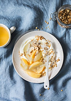 Served breakfast table - caramelized quince with greek yogurt, granola and nuts on a blue background, top view. Delicious healthy