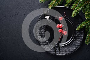 Served christmas table setting empty black ceramic plate on dark background. Christmas Decoration. Holiday Decorations with branch