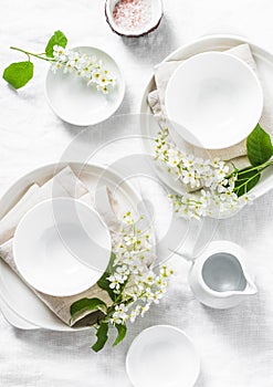 Served empty table with white crockery, flowers, napkins on white background, top view. Cozy home serving food table