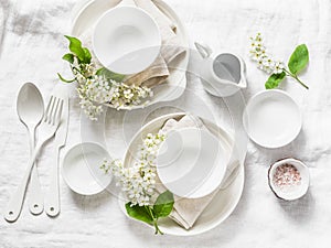 Served empty table with white crockery, flowers, napkins on white background, top view. Cozy home serving food table