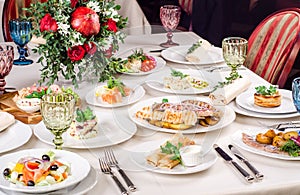 Served for holiday banquet restaurant table with dishes, snack, salads, cutlery, wine and water glasses. European food in a