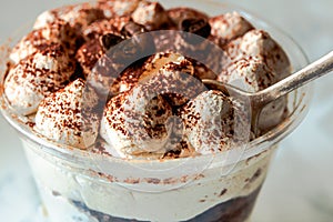 Served Italian dessert Tiramisu, cream, cocoa powder in a plastic take away cup.Healthy food and diet concept, restaurant dish