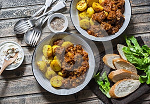 Served lunch table - irish beef stew with bombay turmeric potatoes. Delicious seasonal food on a wooden background, top view.