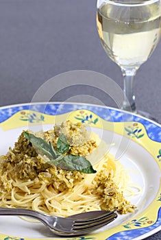 Served pasta with cream sauce and zucchini with glass of white wine