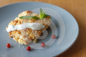 Served slice of freshly baked homemade apple crisp pie with cream and berries on a gray plate