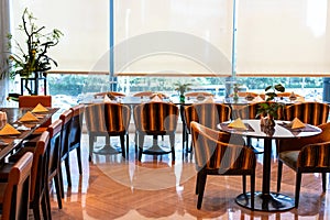 Served tables in the hotel restaurant. The banquet room is ready to receive guests. Roller blinds omitted and a Chinese