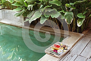 Served tray with fruit plate by hotel pool on Bali villa