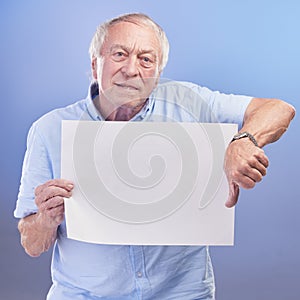 The service around here sucks. Studio shot of a senior man holding a blank sign and showing thumbs down against a blue