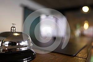 Service bell locating at reception. Silver call bell on table, receptionists on background