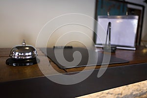 Service bell locating at reception. Silver call bell on table, receptionists on background photo