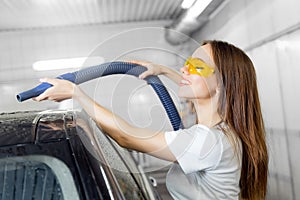 Service car wash express. Girl worker uses turbo dryer to remove drops of water