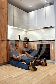 Service company workers sitting on kitchen floor, chatting