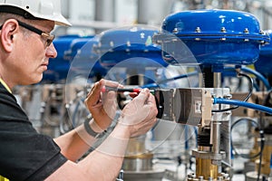 A service engineer checks an pneumatic valve with a screwdriver