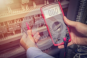 Service engineer with multimeter tester in hands close up. Electrical measurements in electric cabinet. Support specialist