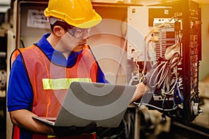 Service engineer team working with electronic wire back panel of heavy industry machine for maintenance repair and fix with laptop