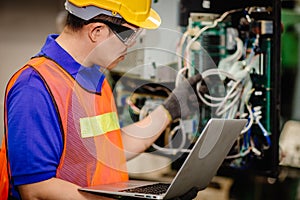 Service engineer team working with electronic wire back panel of heavy industry machine for maintenance repair and fix with laptop