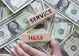 Service here symbol. Concept words Service here on wooden blocks. Beautiful dollar background. Businessman hand. Business and