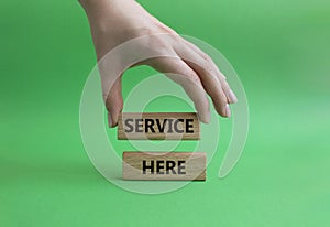 Service here symbol. Concept words Service here on wooden blocks. Beautiful green background. Businessman hand. Business and