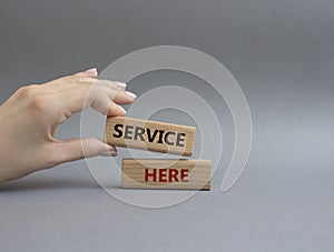 Service here symbol. Concept words Service here on wooden blocks. Beautiful grey background. Businessman hand. Business and