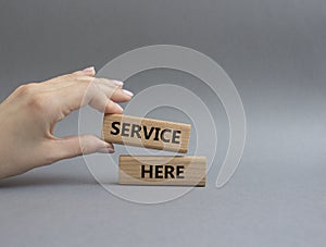 Service here symbol. Concept words Service here on wooden blocks. Beautiful grey background. Businessman hand. Business and