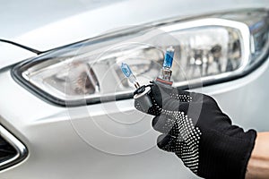 service machanic holds h7 halogen light bulb against of headlight