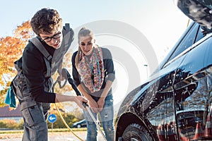 Service man helping woman cleaning her auto in car wash