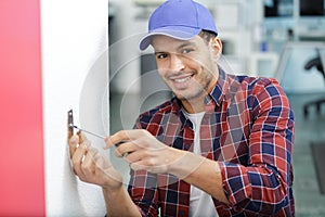 Service man installing power socket in wall with screwdriver