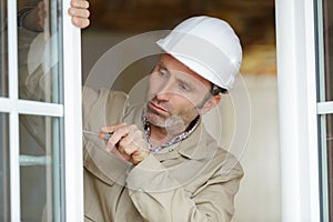 service man installing window with screwdriver