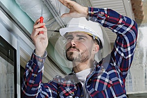 service man installing window with screwdriver